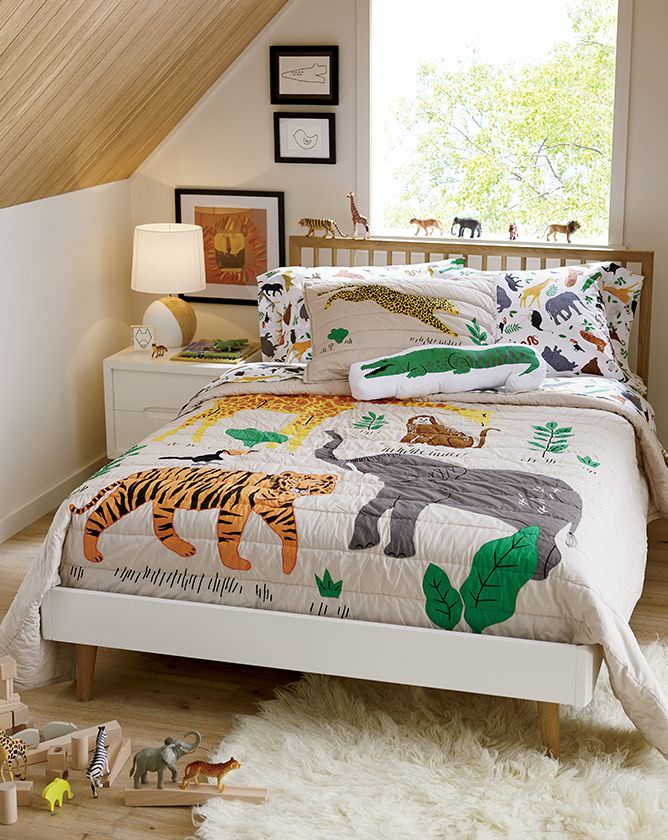 اتاق کودک پسر با تم حیوانات که روی تخت آن روتختی و روبالشی با طرح حیات وحش پهن شده است